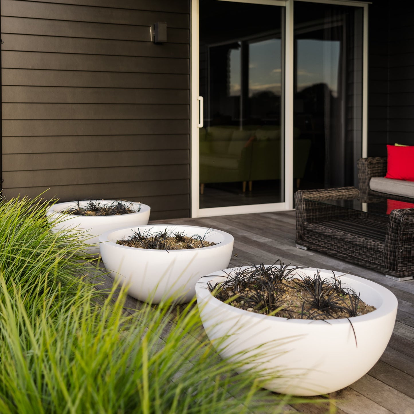 A cluster of three white planter bowls on a deck.