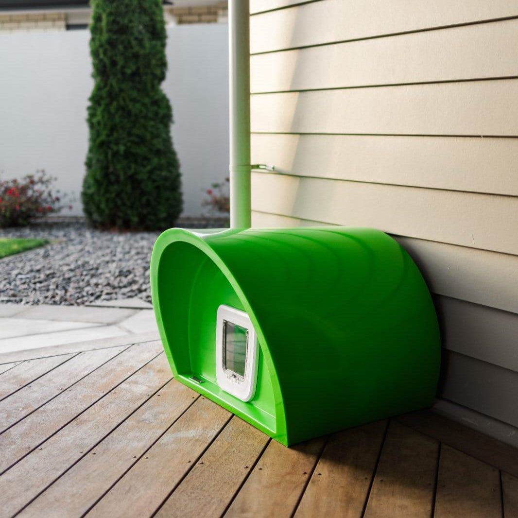 A green Modscene cat house sitting on a deck.
