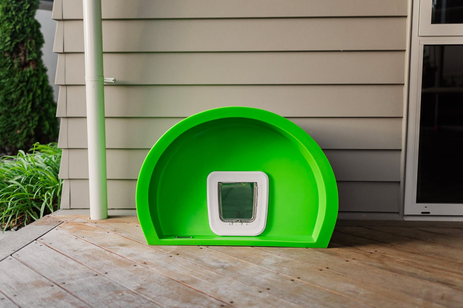 A green Modscene cat house on a wooden deck.