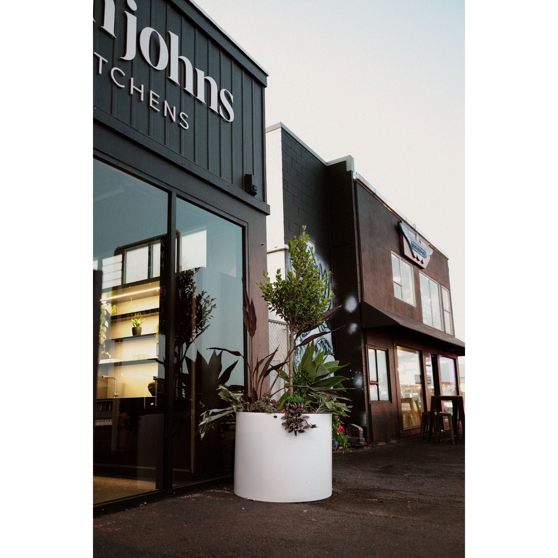 A large white Modscene planter pot on a footpath in the city.