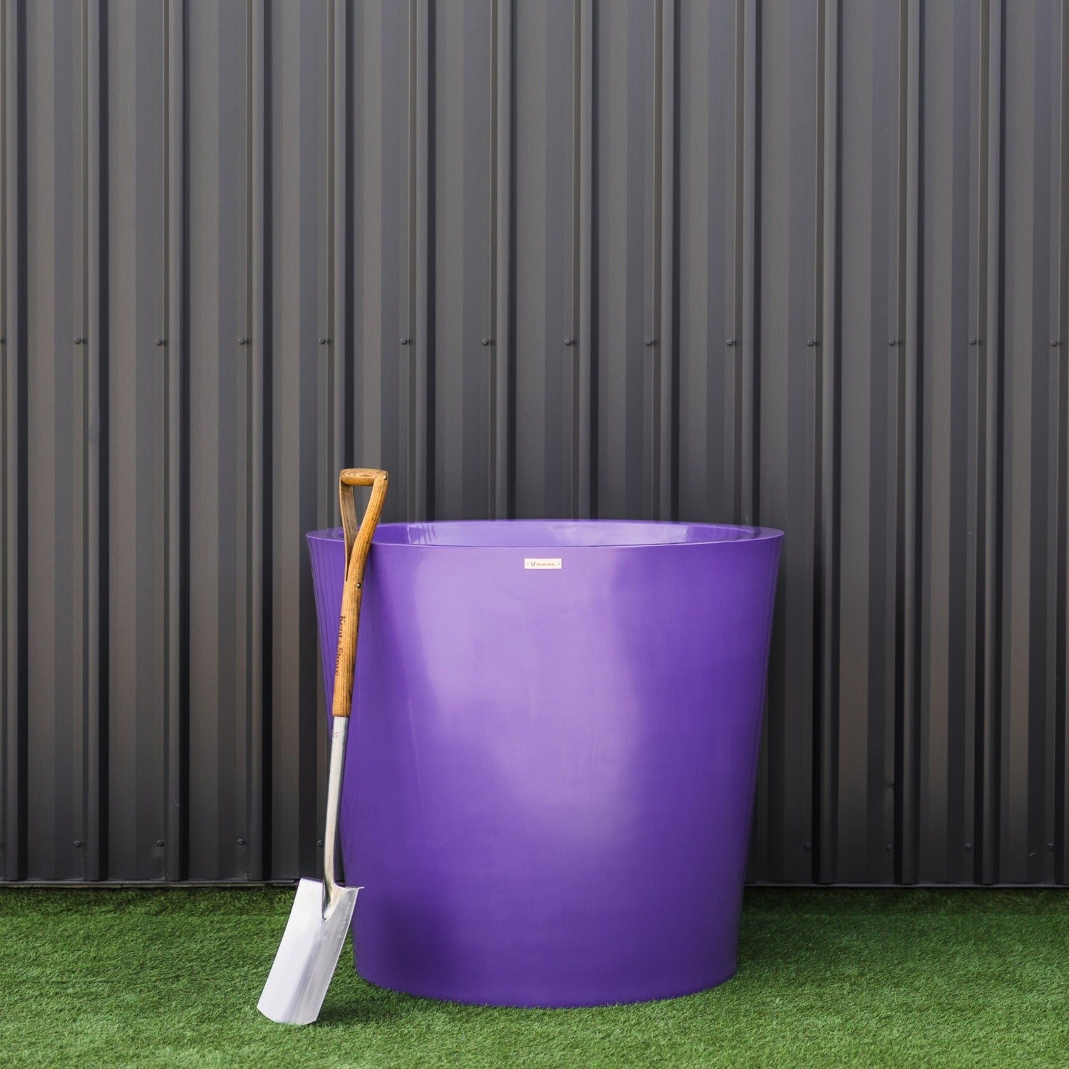 Large colourful planter pot in front of a dark wall.