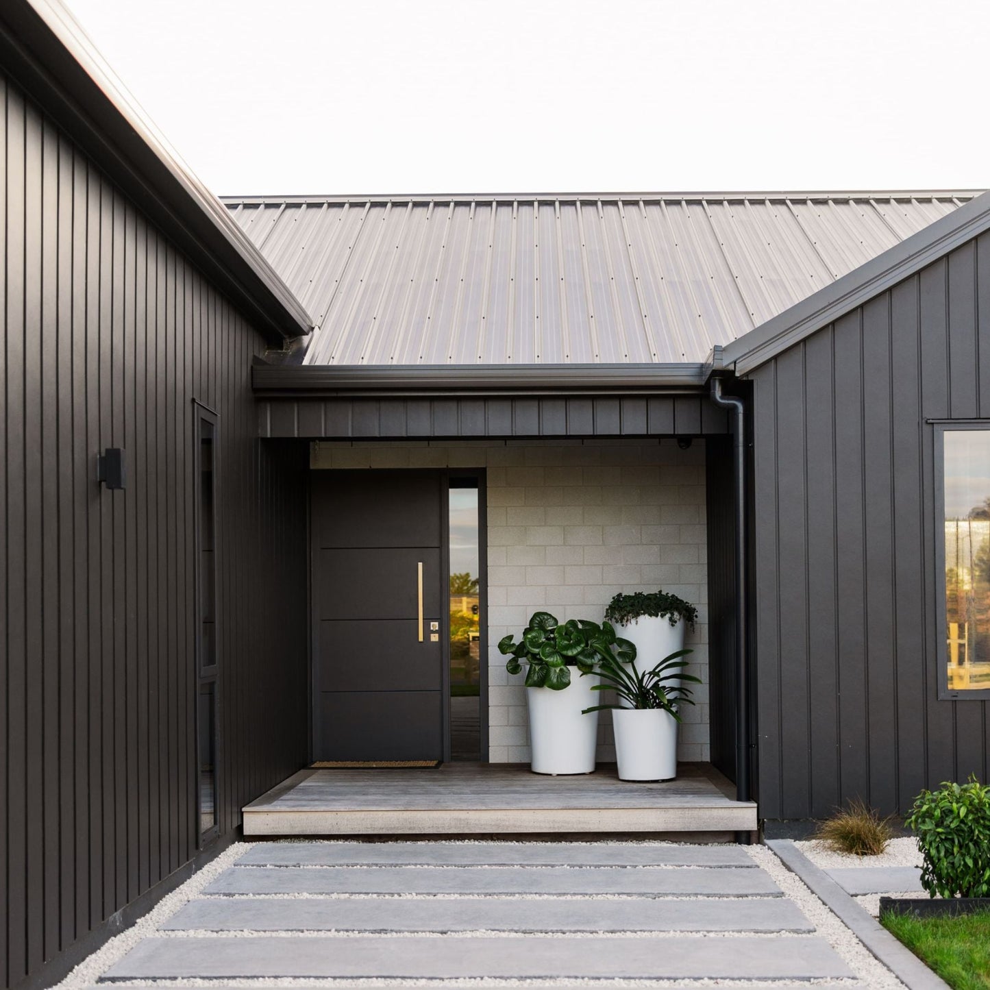 A cluster of three white planters on a deck by the front door of a house. NZ made planters.