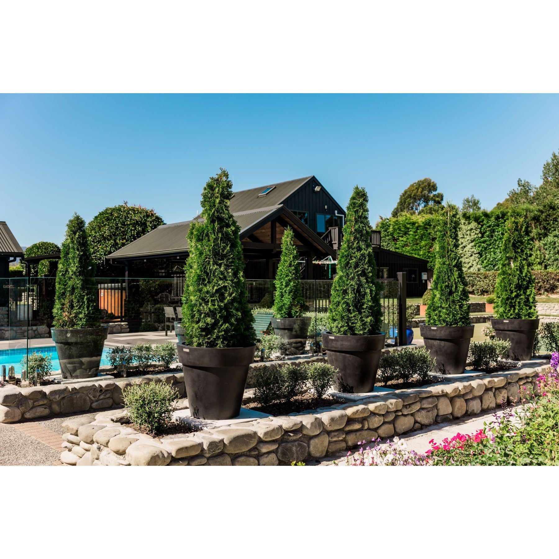 Large Modscene planters in a garden beside a stone walkway.