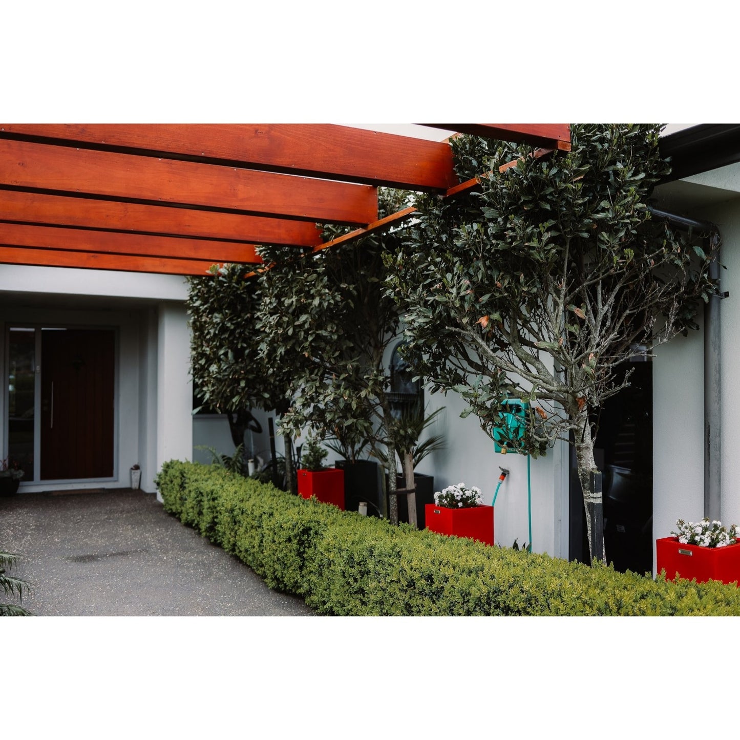 Three apple red planters in a garden amongst the trees.