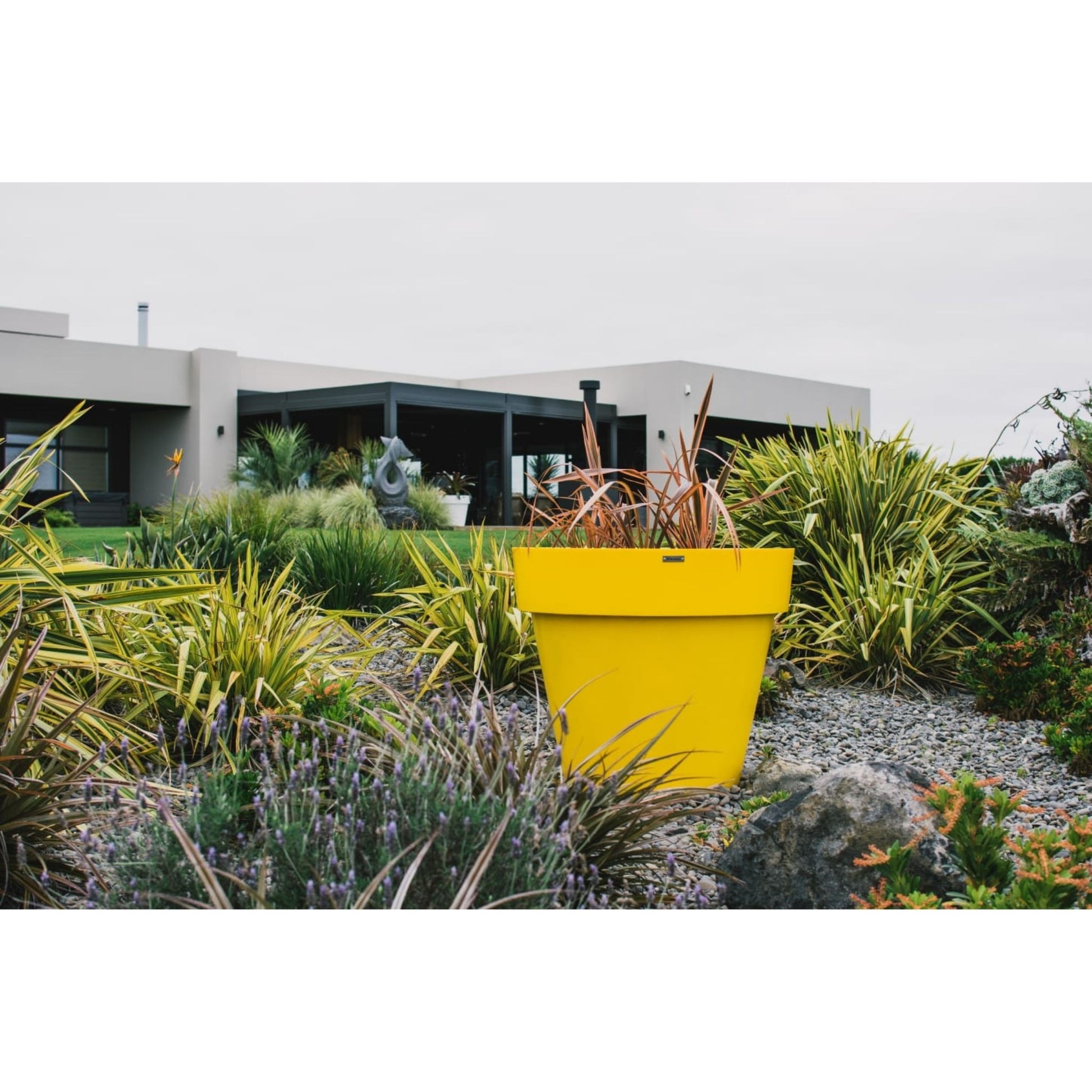 Large yellow feature planter pot in a garden on a large property.