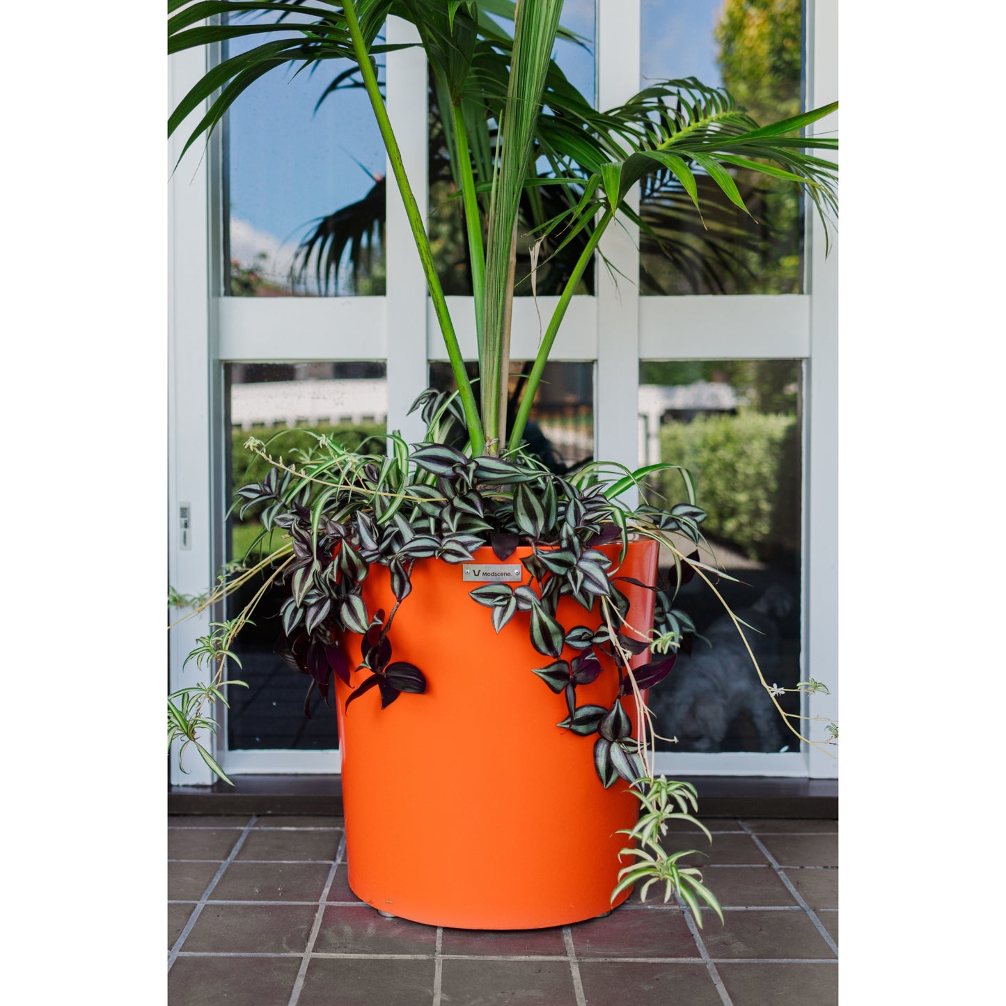 A high quality lightweight orange coloured planter pot with a palm tree in it.