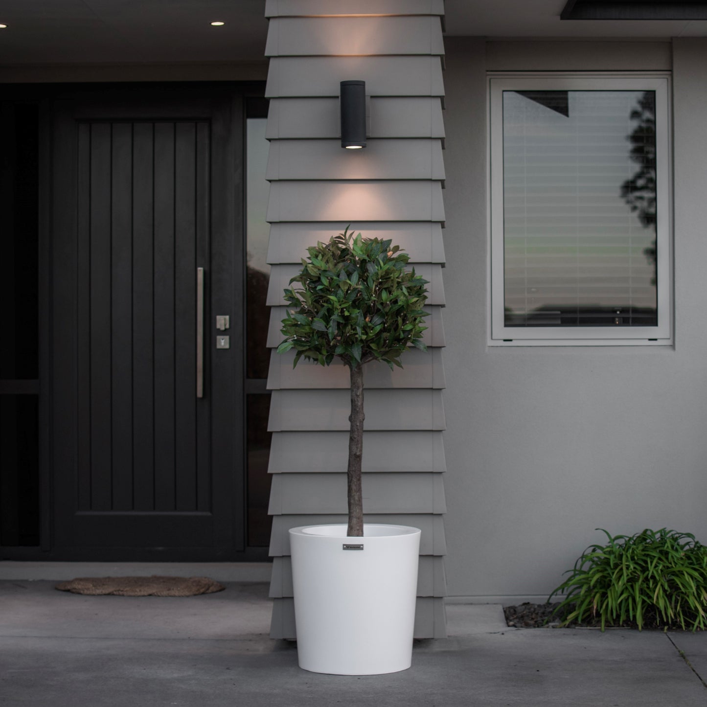 Milan planter pot in front of a house pillar.