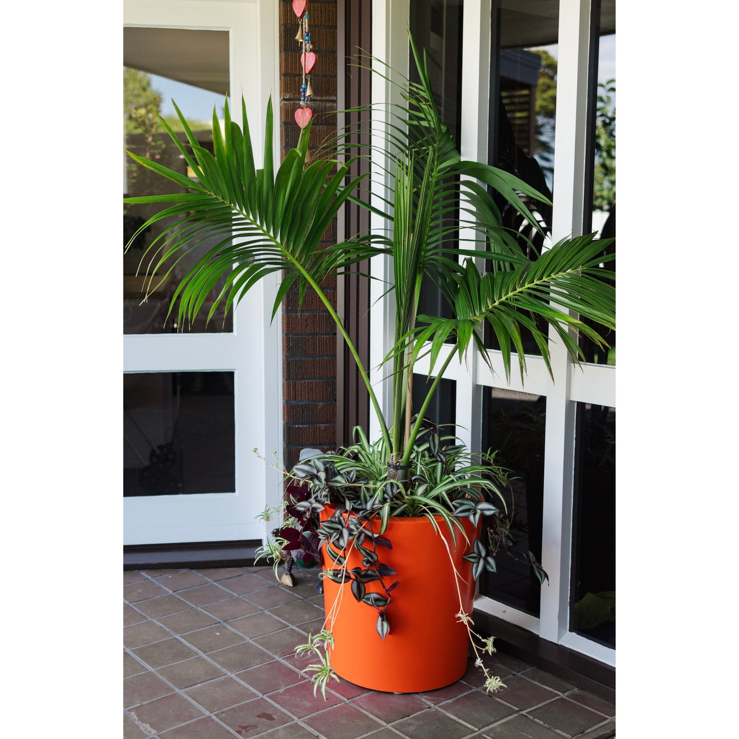 A large orange colour planter pot by an entranceway.
