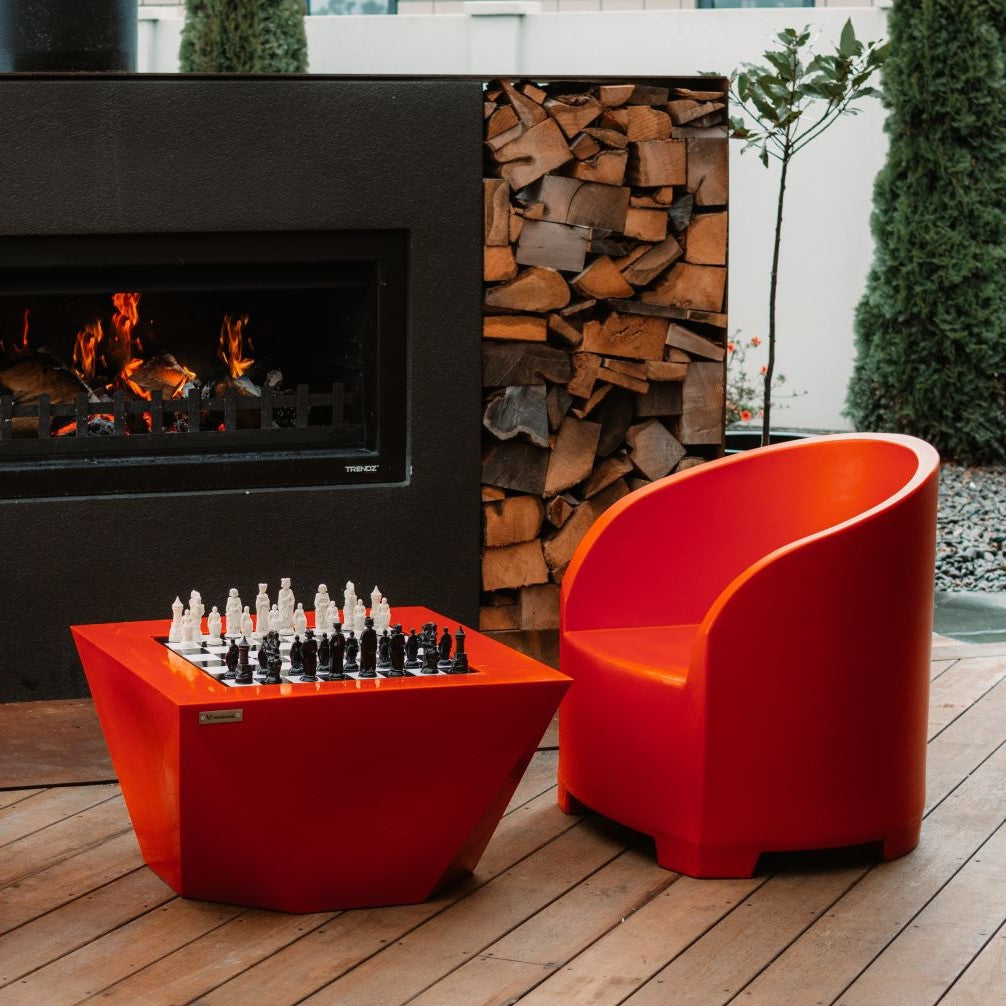 Colourful orange outdoor furniture on a deck by an outdoor fire.