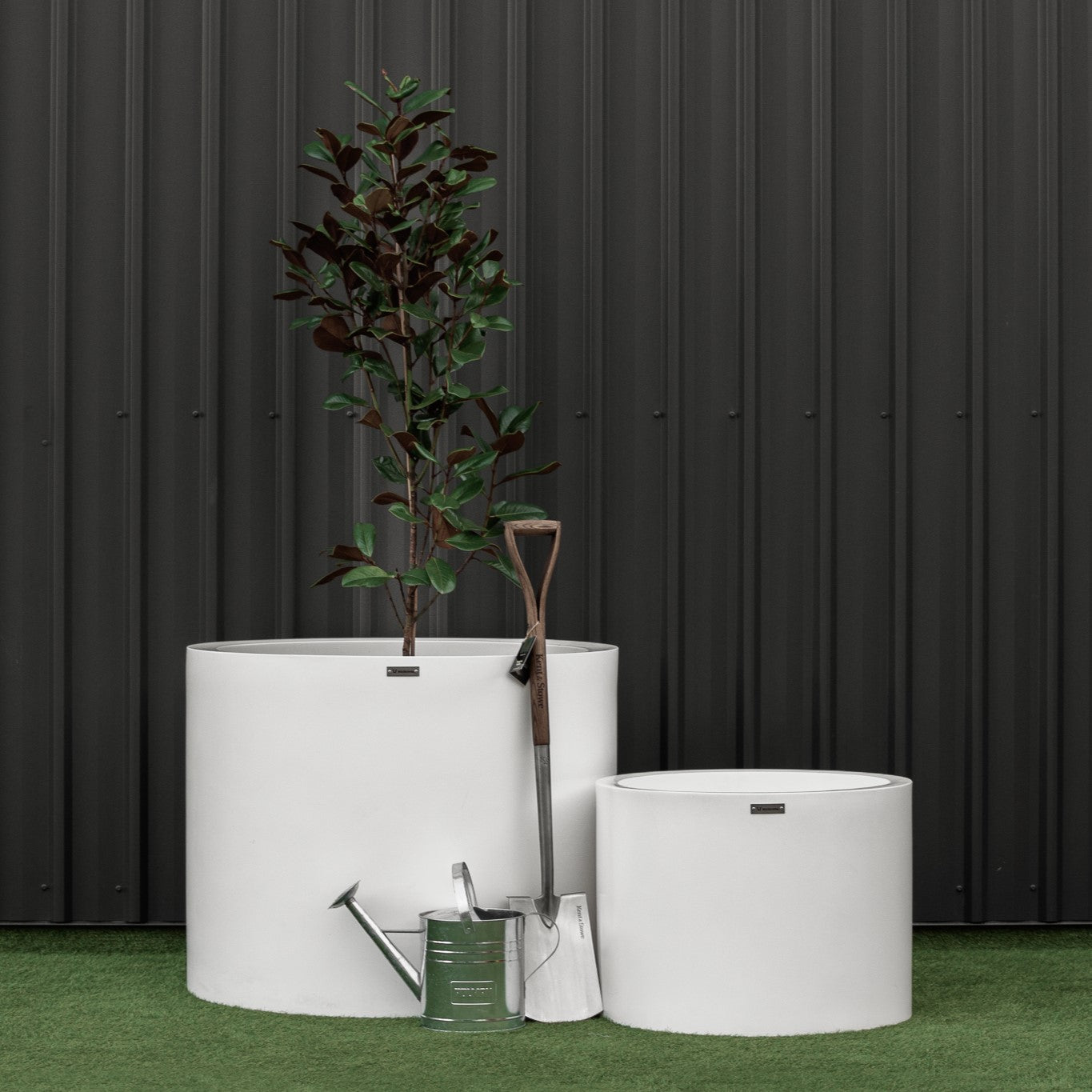 Large Modscene cylinder planters in front of a black wall.