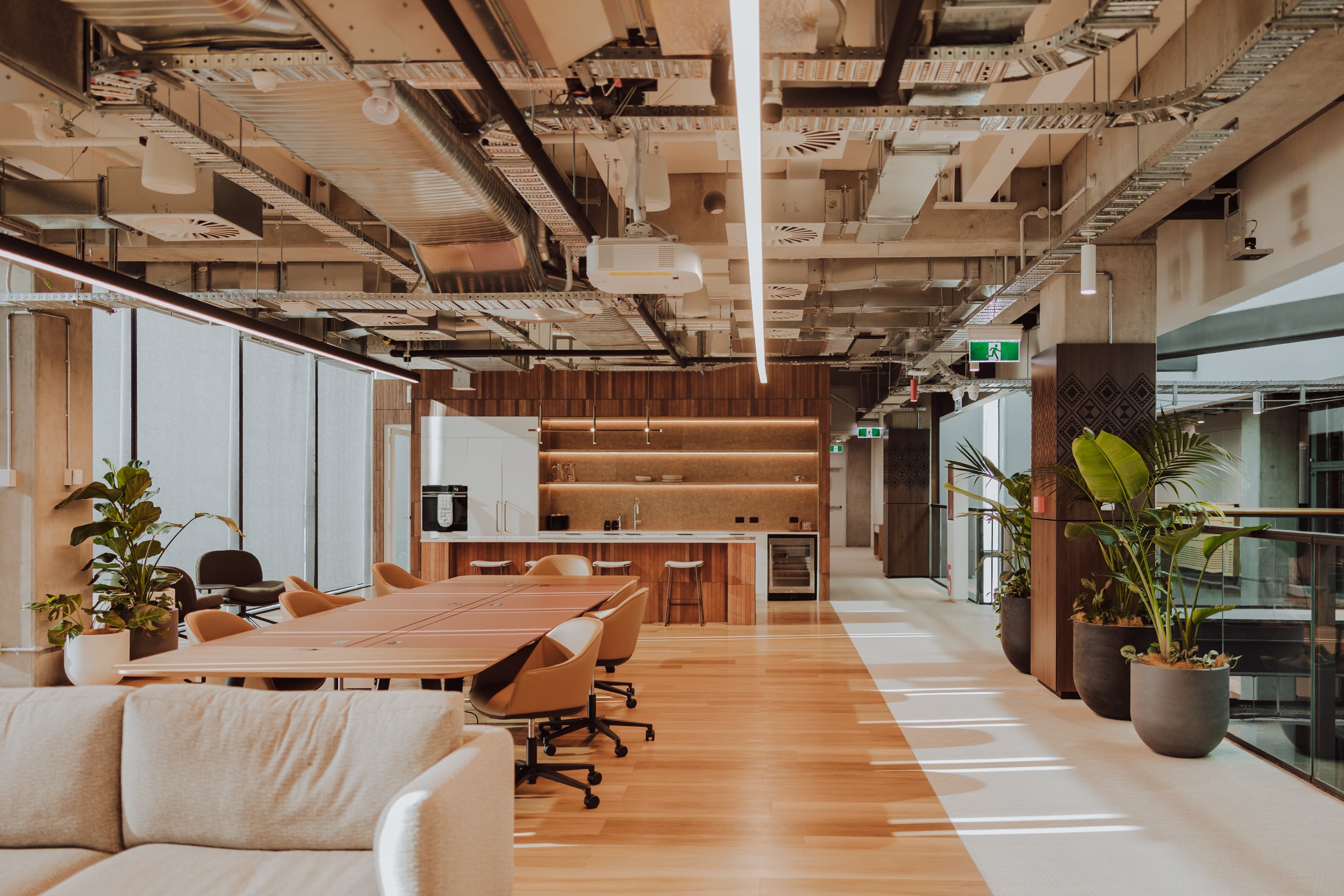 Modern office space with wooden floors, large windows, and a casual work area.