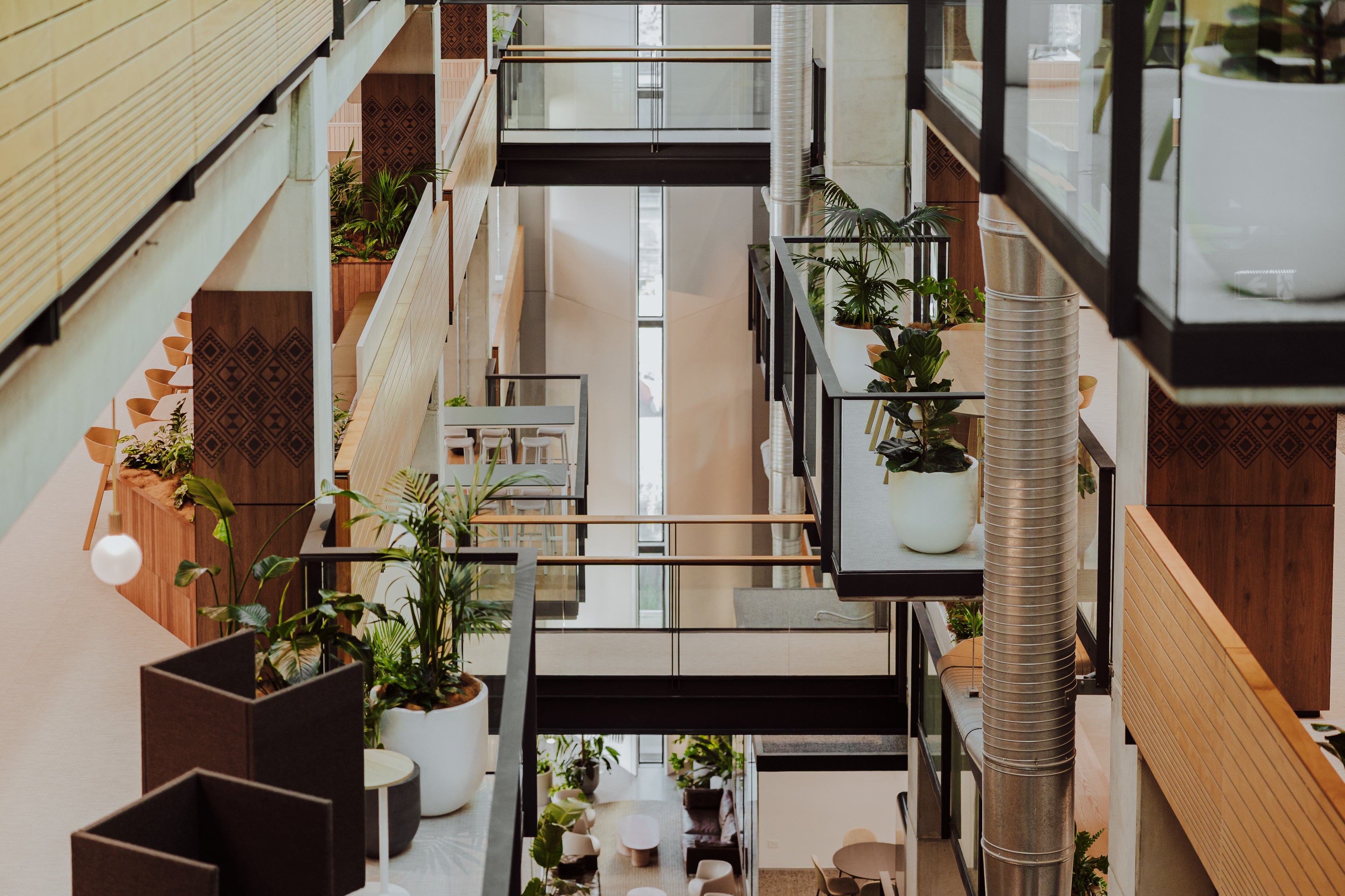 Modern indoor setting with glass railings, plants, and a staircase.