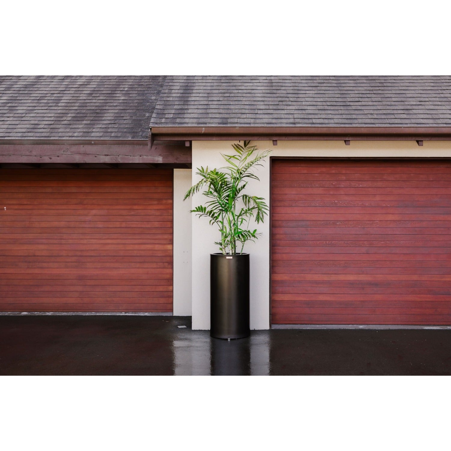 A large black Modscene cylinder planter in front of a house.