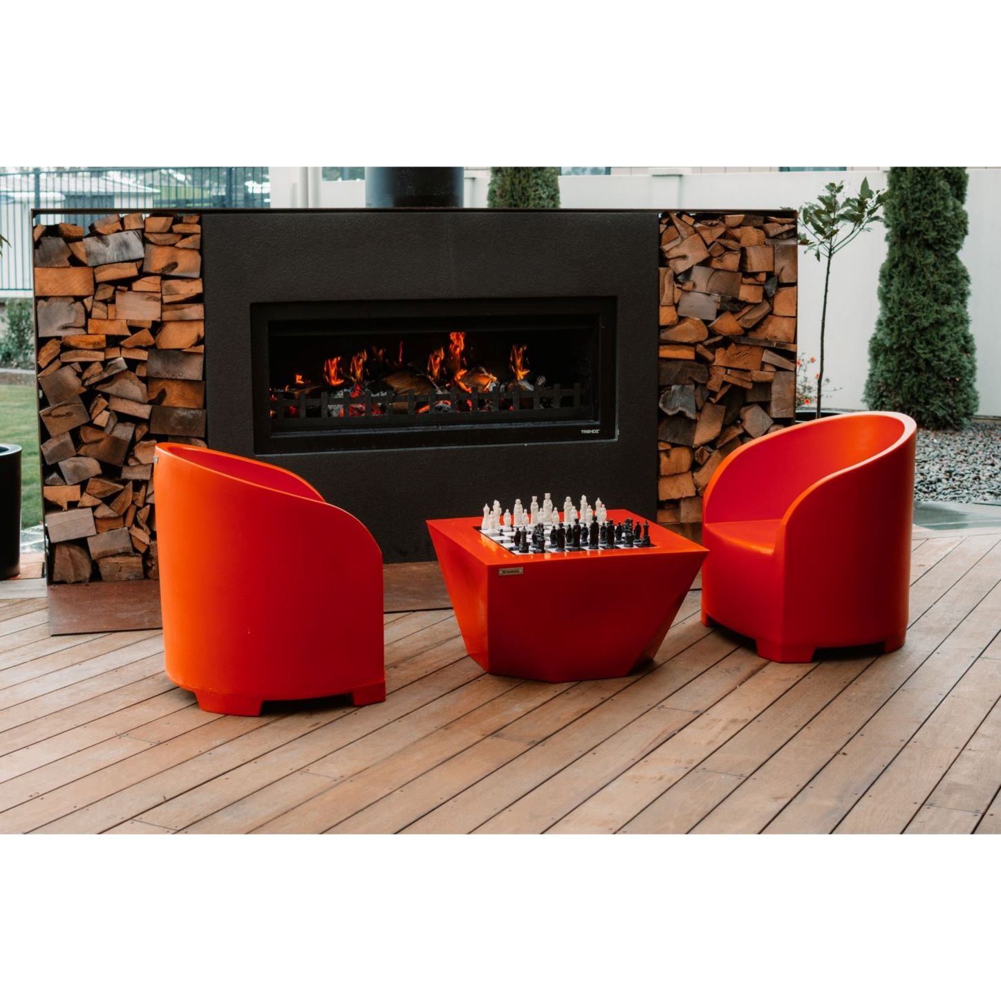 Orange Modscene outdoor furniture on a patio in front of a Trendz Outdoors fireplace.