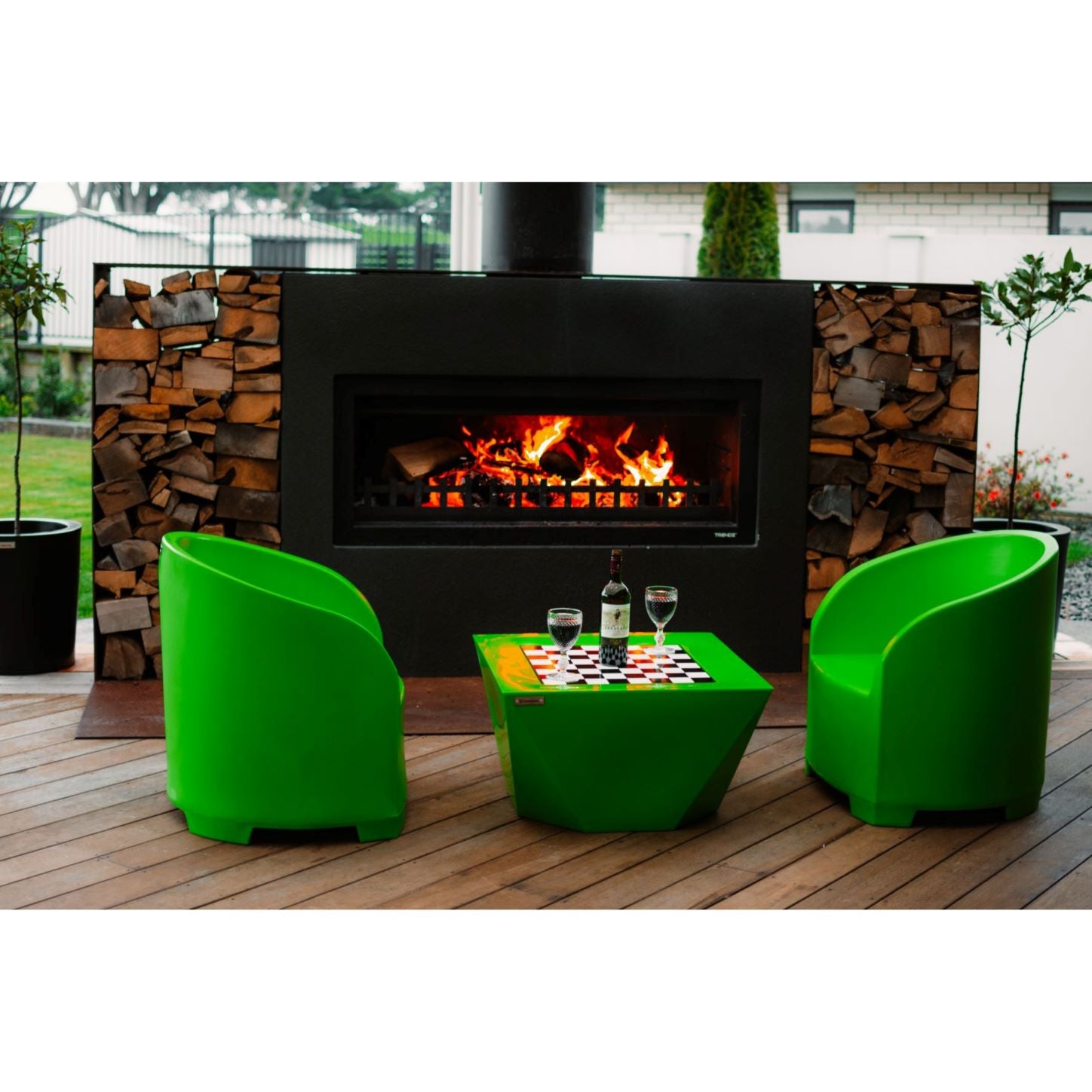 Lime green outdoor furniture on a deck in front of a Trendz Outdoors fireplace.