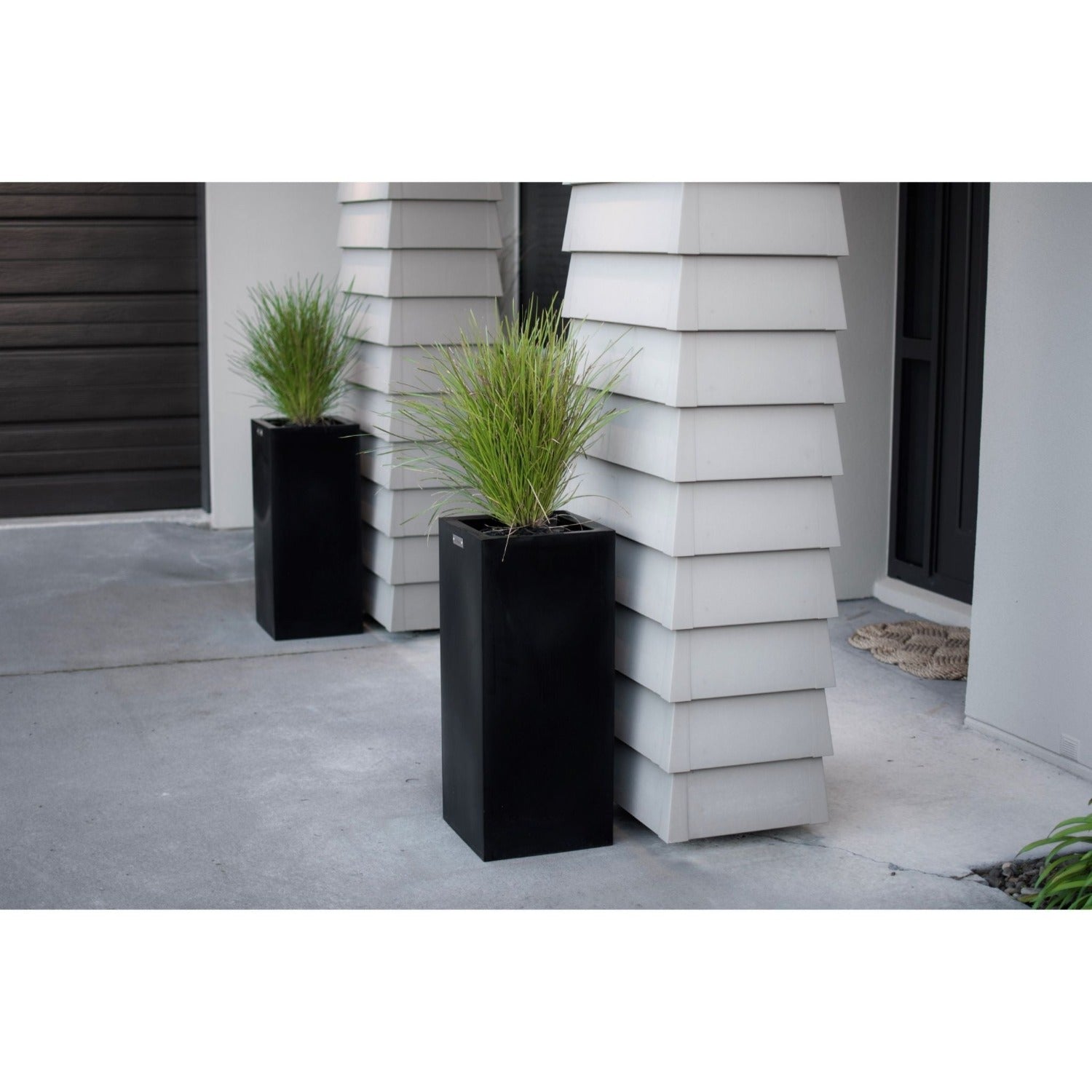 Two black planter pots planted with grasses.