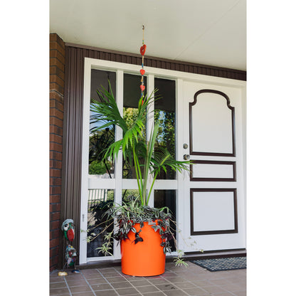 Orange Modscene planter pot by a front door. The planter is bright orange and has a palm in it.