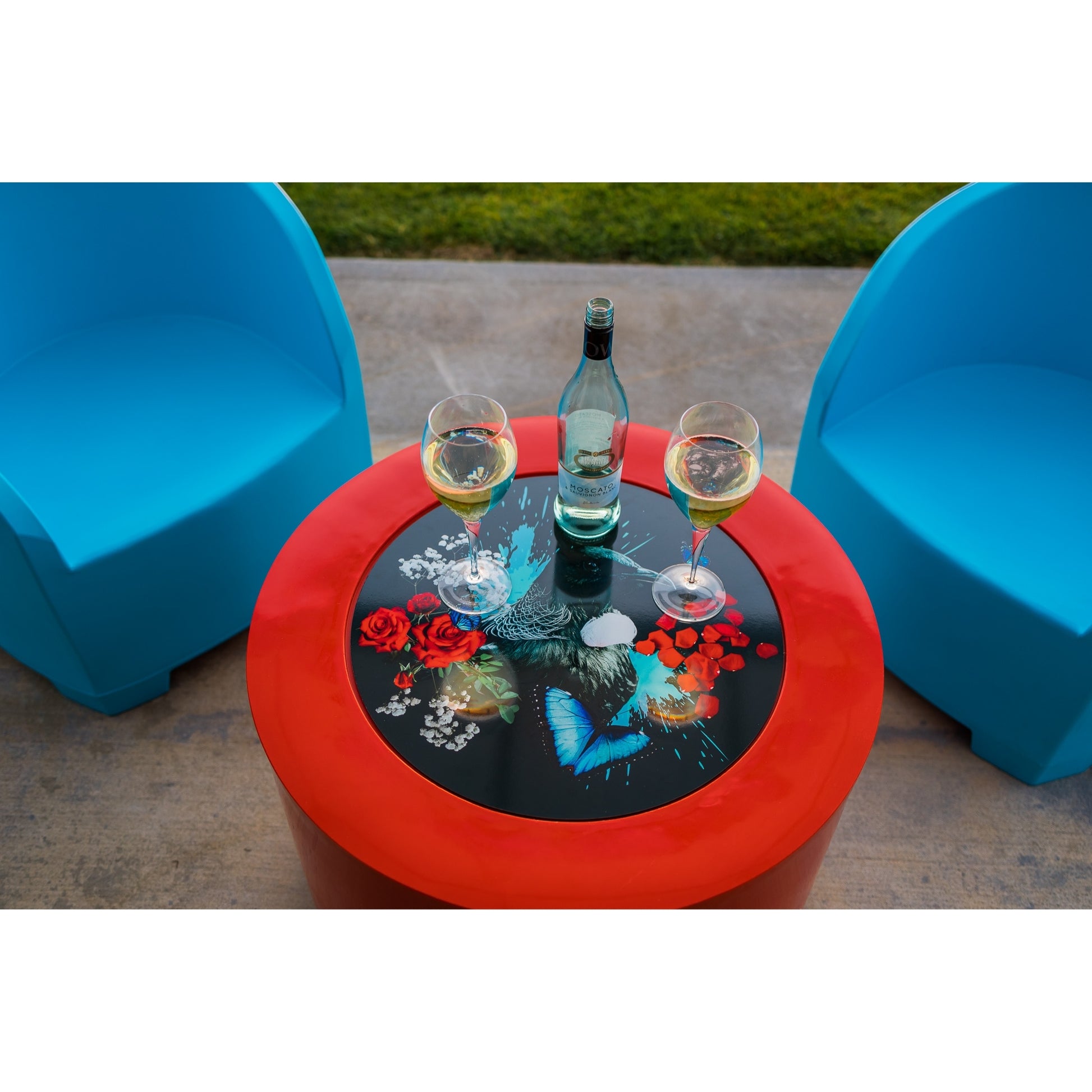 Two blue chairs and a red cylinder table on a patio area.